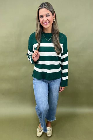 Green and white striped knit sweater styled with light wash wide leg frayed hem jeans and gold loafers