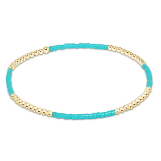 Turquoise beaded bracelet with gold accents on a white background