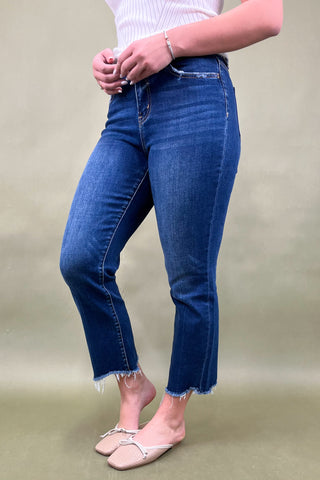 Person wearing blue jeans and a white top on a plain background