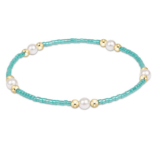 Turquoise beaded bracelet with pearls and gold accents on a white background