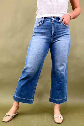 Person wearing blue jeans and a white top on a green background