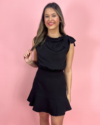 Woman wearing a black dress against a pink background