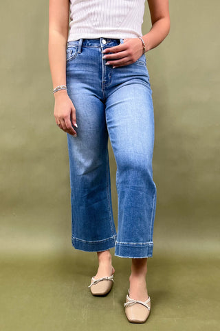 Person wearing blue jeans and a white top on a green background