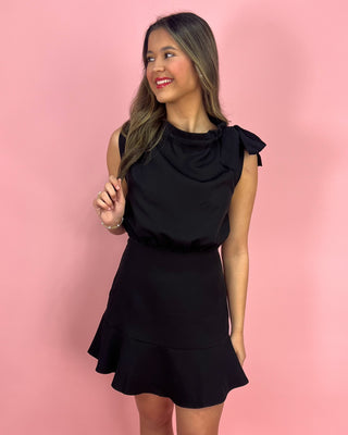 Woman wearing a black dress against a pink background