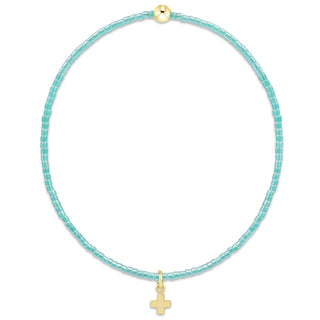 Turquoise beaded necklace with a gold cross pendant on a white background