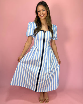 Woman wearing a blue and white striped dress against a pink background