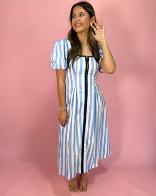 Woman wearing a blue and white striped dress against a pink background