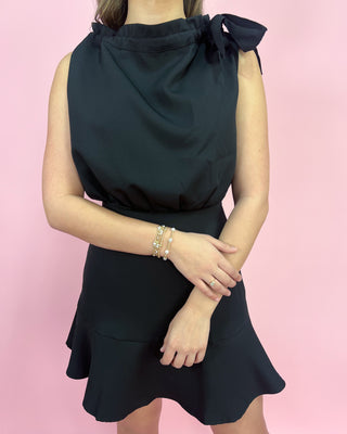 Black dress with bow detail on a pink background