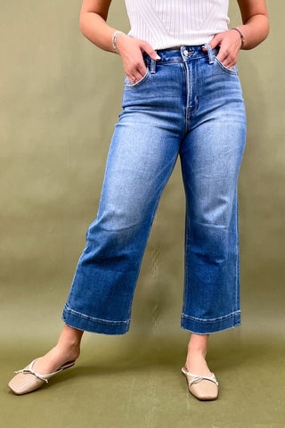 Person wearing blue jeans and a white top on a green background