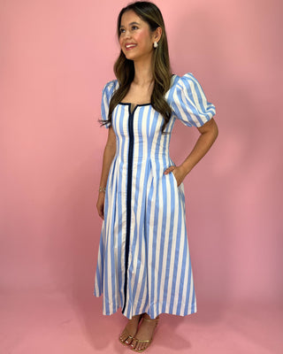 Woman wearing a blue and white striped dress against a pink background