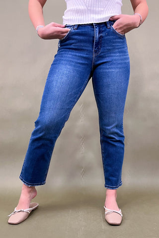 Person wearing blue jeans and a white top on a plain background