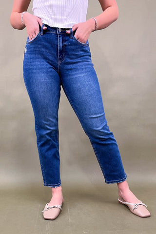 Person wearing blue jeans and a white top against a plain background