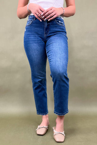Person wearing blue jeans and beige shoes on a plain background
