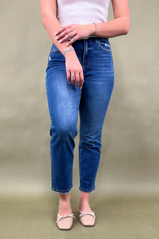 Person wearing blue jeans and a white top on a beige background