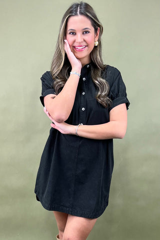 Woman wearing a black dress against a green background