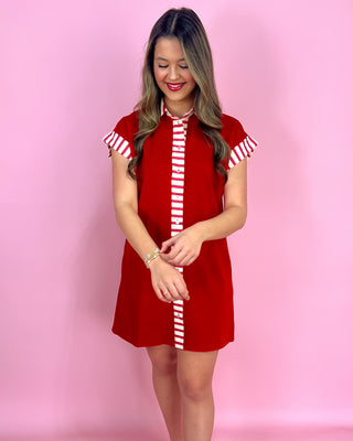 Woman wearing a red dress with white stripes on a pink background