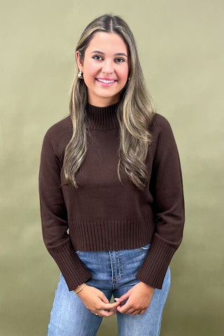 Chocolate brown mock neck sweater styled with light wash wide leg frayed hem jeans and gold loafers