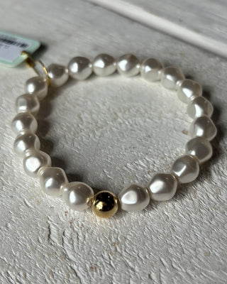 Pearl bracelet with a gold bead on a light gray surface