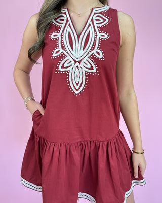 Red dress with white embroidery on a pink background