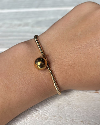 Gold bracelet on a wrist with a light background