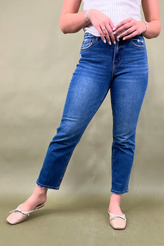 Person wearing blue jeans on a plain background