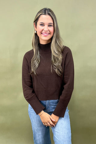Chocolate brown mock neck sweater styled with light wash wide leg frayed hem jeans and gold loafers