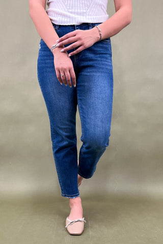 Person wearing blue jeans and a white top on a beige background