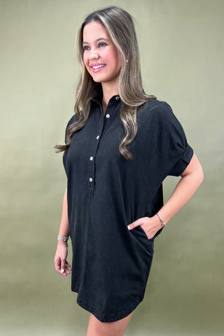 Woman wearing a black dress against a beige background