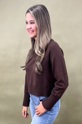 Chocolate brown mock neck sweater styled with light wash wide leg frayed hem jeans and gold loafers