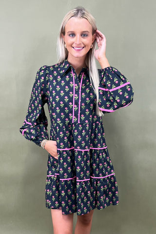 Woman wearing a floral dress with pink accents against a plain background