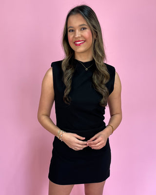 Woman wearing a black dress against a pink background