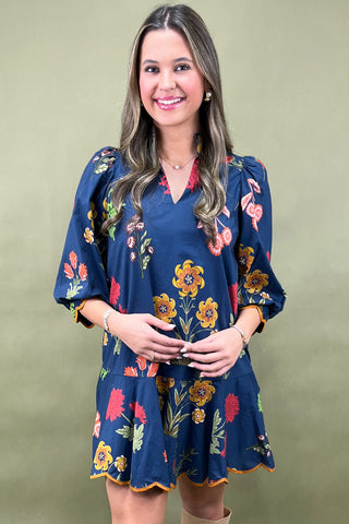 Woman wearing a navy floral dress against a green background