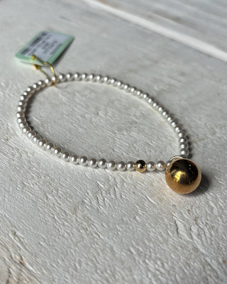 Pearl bracelet with a gold bead on a light gray surface