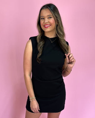Woman wearing a black dress against a pink background