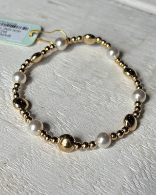 Bracelet with gold beads and pearls on a light wooden surface