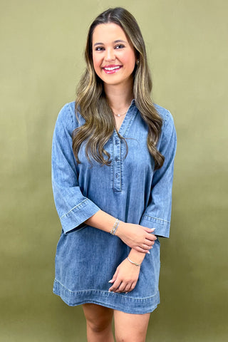 Woman wearing a denim dress against a green background