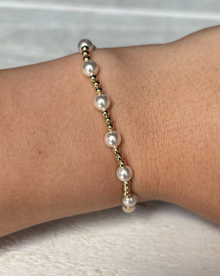Pearl bracelet on a wrist with a neutral background