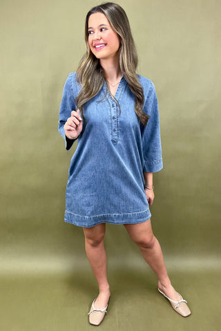 Woman wearing a blue denim dress against a green background