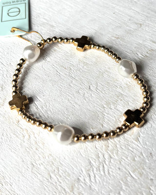 Bracelet with gold beads and black clover-shaped charms on a white background