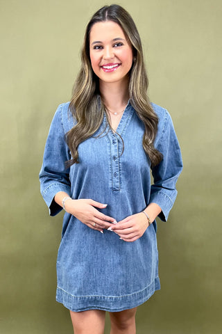 Woman wearing a blue denim dress against a green background