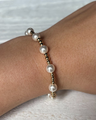 Pearl bracelet on a wrist against a neutral background