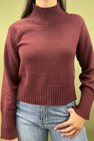 Burgundy mock neck sweater styled with light wash wide leg frayed hem jeans and gold loafers