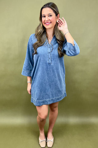 Woman wearing a blue denim dress against a green background