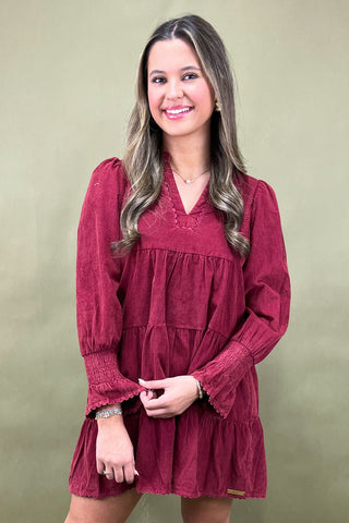 Woman wearing a burgundy dress against a plain background