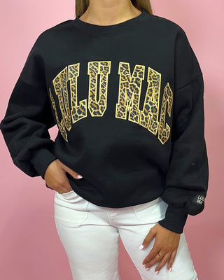 Black sweatshirt with gold leopard print text on a pink background