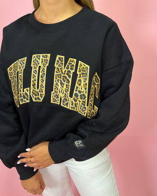 Black sweatshirt with gold leopard print text on a pink background