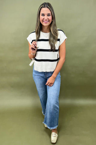 Black and white striped knit top with side bow details styled with light wash wide leg frayed hem jeans and gold loafers.
