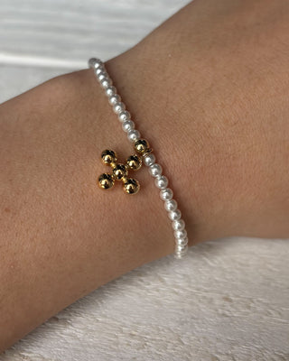 Pearl bracelet with gold beads on a wrist against a neutral background