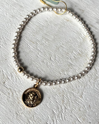 Pearl bracelet with a gold charm on a light gray surface