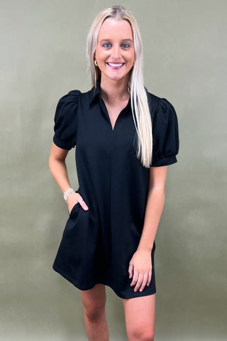 Woman wearing a black dress against a plain background